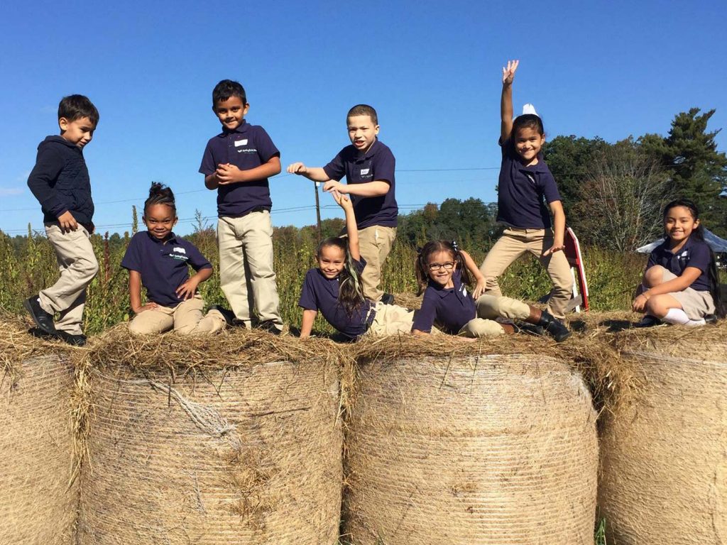 Kids from Springfield Prep play on hay bales